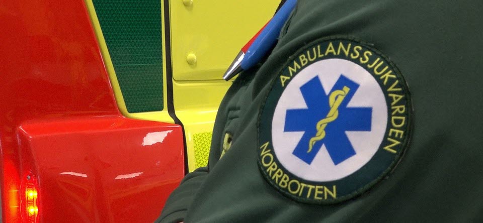 n&auml;rbild p&aring; del av ambulans och en arm med logga f&ouml;r ambulanssjukv&aring;rden i Norrbotten